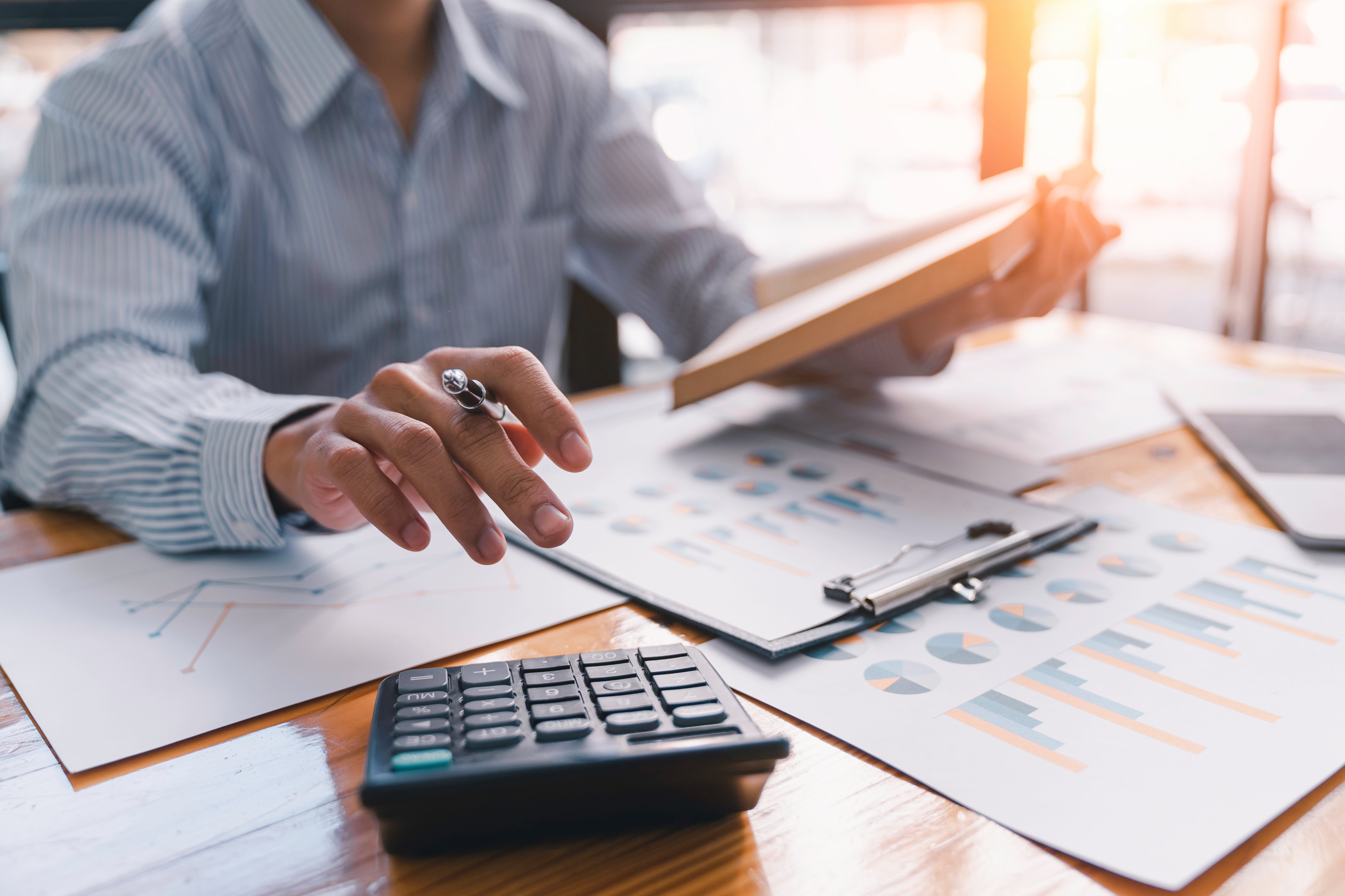 Cette image représente une personne calculant son retour sur investissement à l'aide de graphiques et d'une calculatrice
